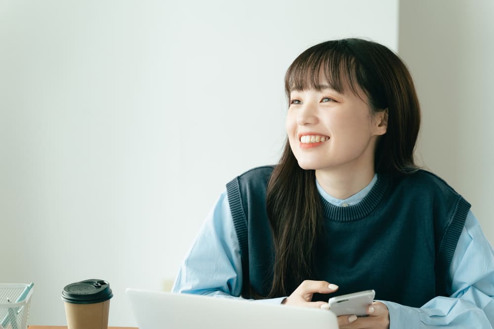 携帯を片手に笑っている女性